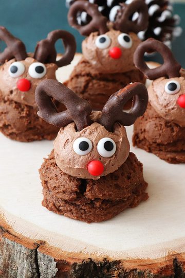 A wood slab with four reindeer drop cookies on it.